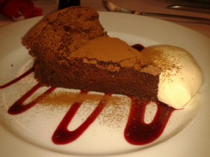 slice of chocolate torte ready to eat with raspberry ju and clotted cream
