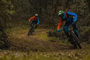 two men dirt biking in a forest
