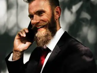 bearded man in suit and red tie