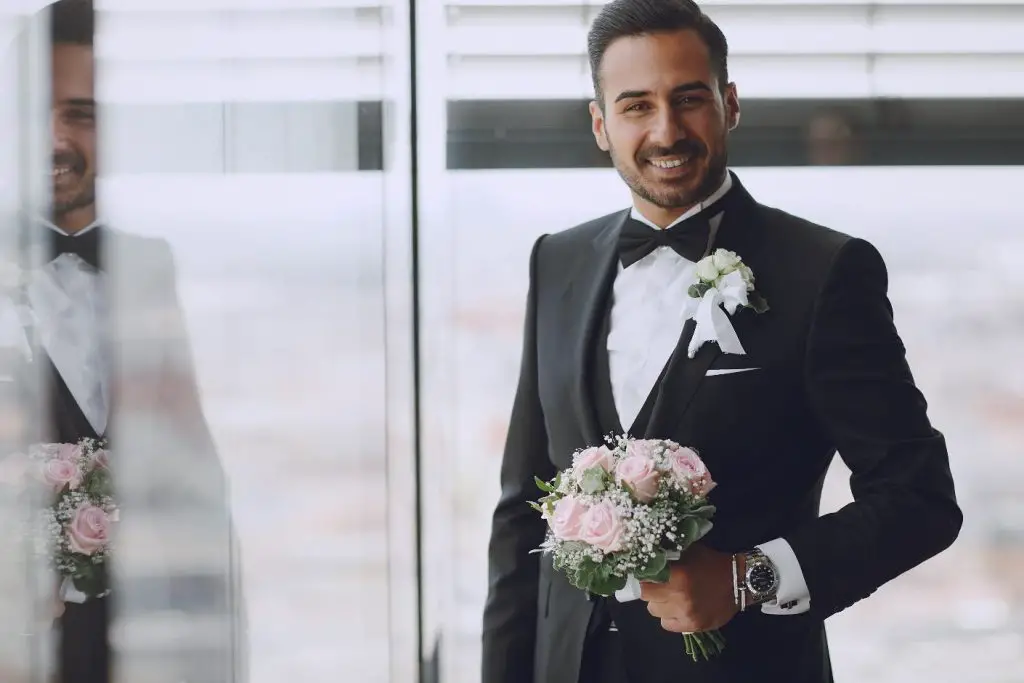 smiling groom holiding a bouquet