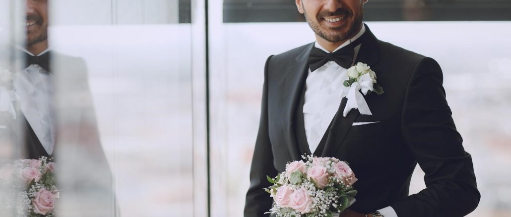 smiling groom holiding a bouquet smiling groom holiding a bouquet